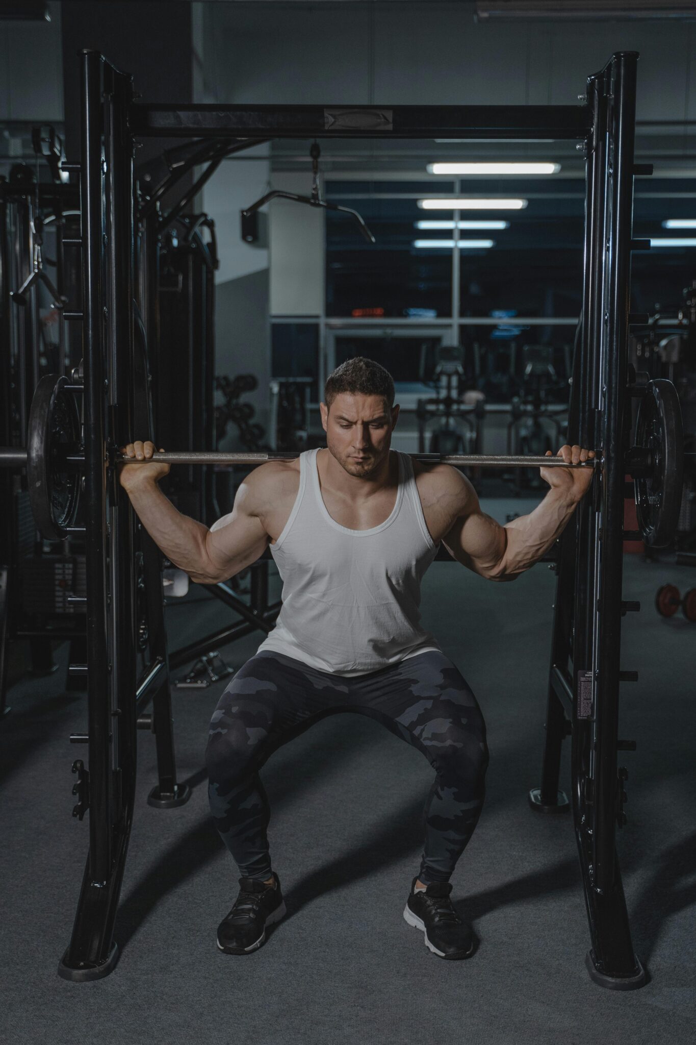 Strong man performing squat with barbell in a gym, showcasing strength and fitness.